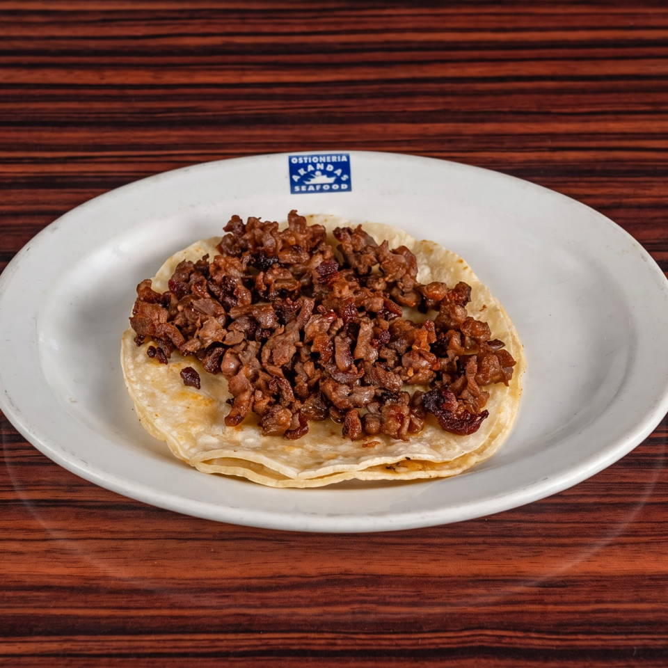 A single taco with a generous portion of diced meat on a white plate with a restaurant logo.